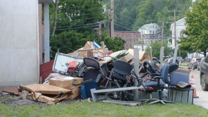 A pile of flood-damaged furniture, equipment, supplies, and materials by the curb.